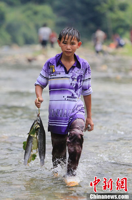 圖為7月9日，一名男孩在鬧魚節活動中抓到了兩條魚。譚凱興 攝