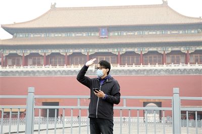 11月1日，北京大部分地區(qū)重度污染，一名游客戴著口罩在午門前揮手跟朋友打招呼。 實(shí)習(xí)生 王飛 攝