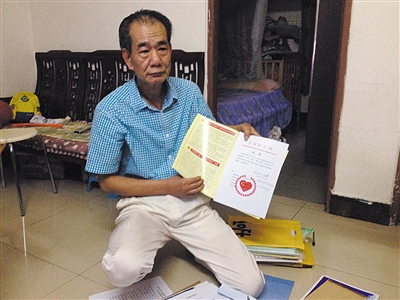翻出一家網站贈予的“中國好人”證書，區少坤單膝跪在地上，“你看，我是中國好人啊?！?范春旭 攝