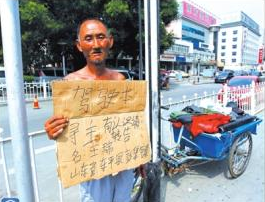 老人舉著牌子在路邊等候失主。京華時報記者譚青攝