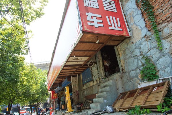 南京一電動車店老板為節約成本蝸居廣告箱