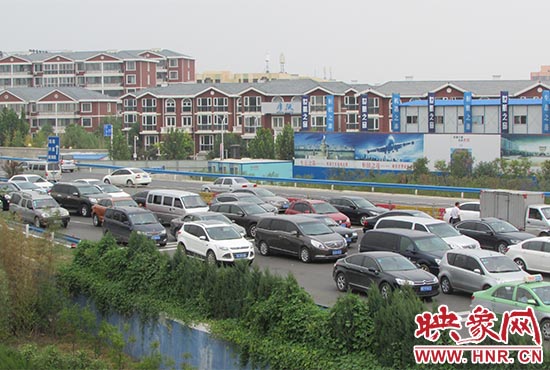 記者看到鄭州機(jī)場(chǎng)收費(fèi)站口車(chē)輛排隊(duì)，與此形成鮮明對(duì)比的是，路的對(duì)面（另一半幅）卻車(chē)輛較少，通行順暢。