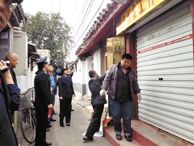 執(zhí)法人員拆除胡同里一家店面未經(jīng)審批的招牌。