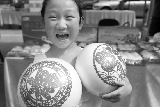 在2013河南食品安全宣傳周活動現場，一個小女孩抱著參展的特色大饅頭樂開了花