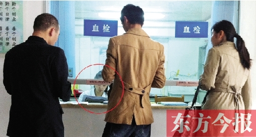昨日，鄭州市二七區(qū)疾控中心辦證大廳，血檢窗口內(nèi)一名女工作人員，邊接受辦證者咨詢邊看報紙