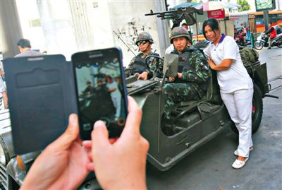 20日，泰國首都曼谷，一名婦女與執行軍管任務的士兵合影。