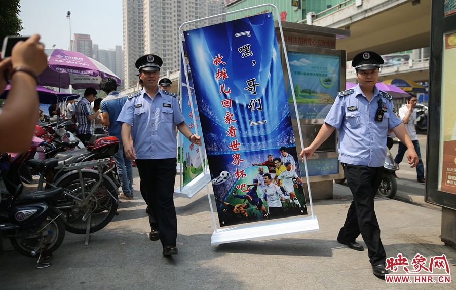 7月2日上午，鄭州市紫荊山地鐵站出入口，執(zhí)法人員抬著寫有勸導(dǎo)語的宣傳板，前往占道經(jīng)營攤位“圍觀執(zhí)法”