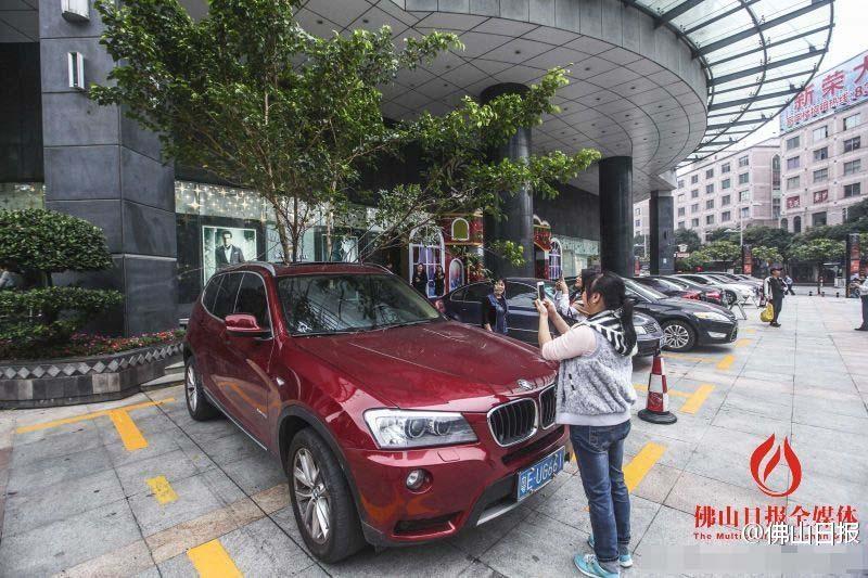 一輛停在停車位上的寶馬轎車，被墜落的樹枝砸中，樹枝徑直插入車內(nèi)，現(xiàn)場(chǎng)引發(fā)不少市民圍觀拍照。