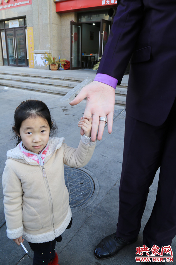巨人“張歡”牽著一名漂亮的小女孩，兩人的手大小對比非常明顯。