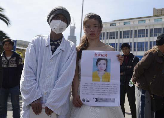 昆明火車站廣場(chǎng)上，24歲的黃習(xí)菊身穿潔白的婚紗，帶著身患白血病的弟弟征婚。
