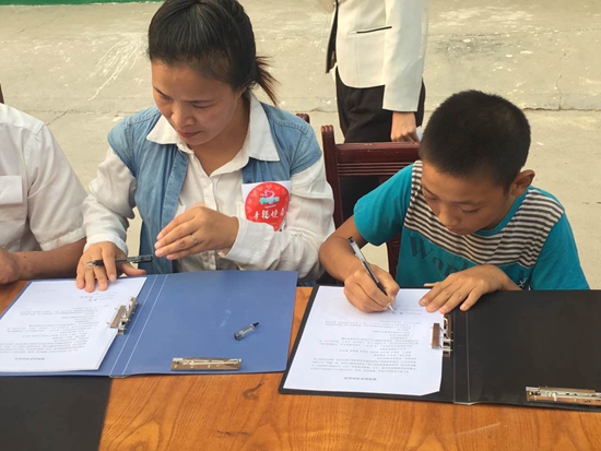 赤腳“小電工”張闖與結對幫扶的幸福使者代表在簽幫扶協議 攝影 張麗