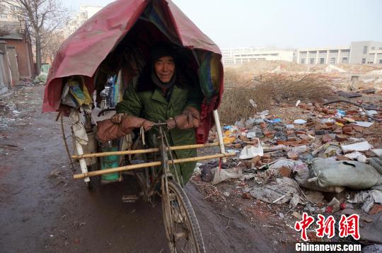 圖為老人走出窩棚，推著三輪車準備出去撿拾廢品。周小云 攝